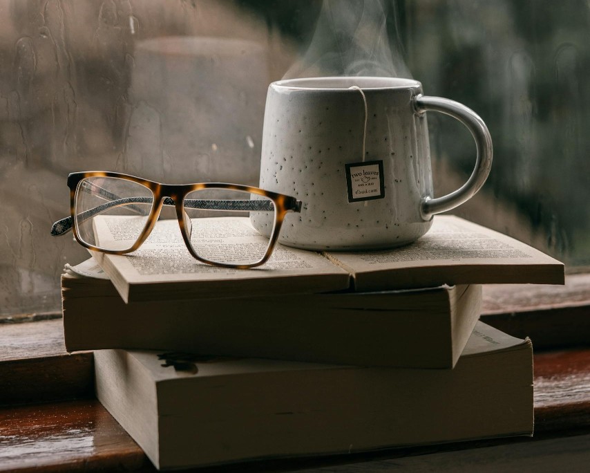 cozy scene of a cup of tea on books with glasses